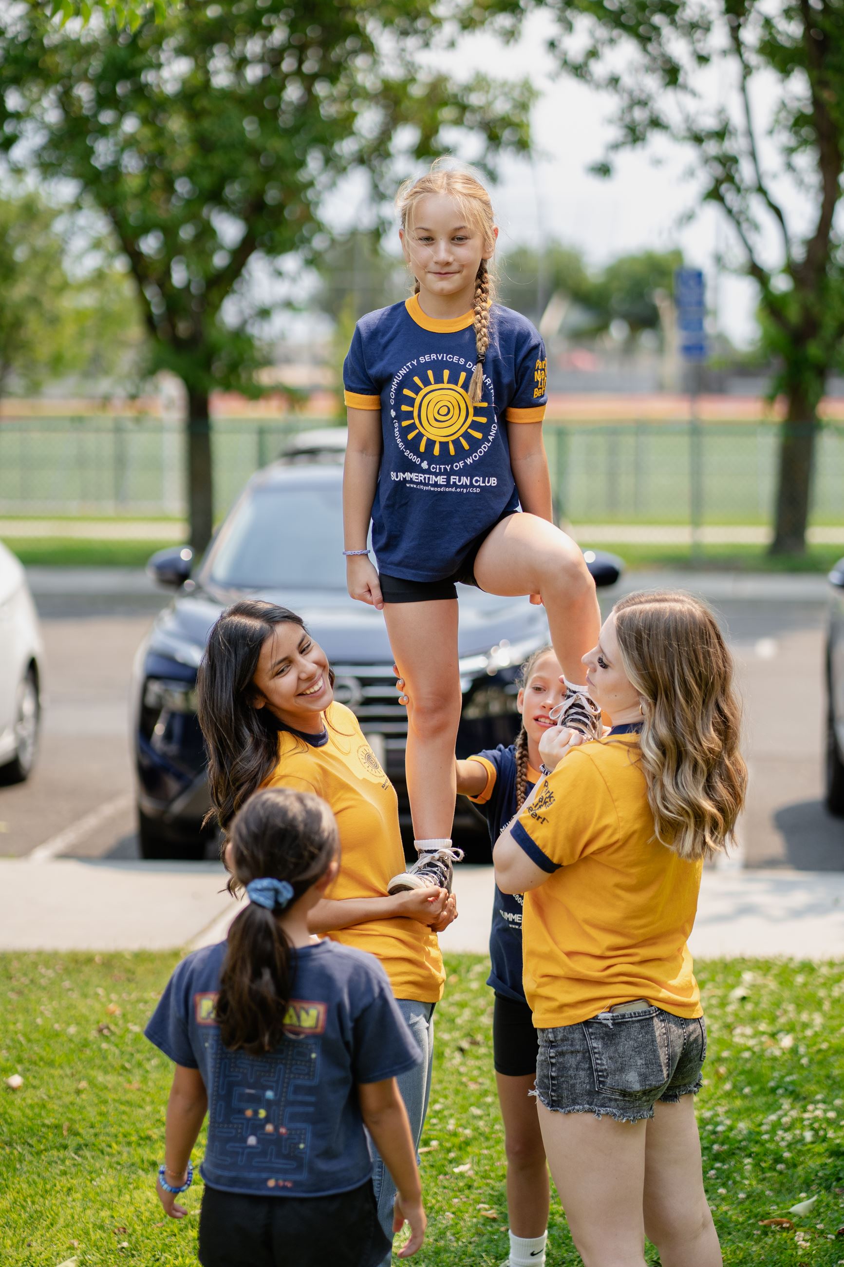 Several girls holding up one other girl smiling 