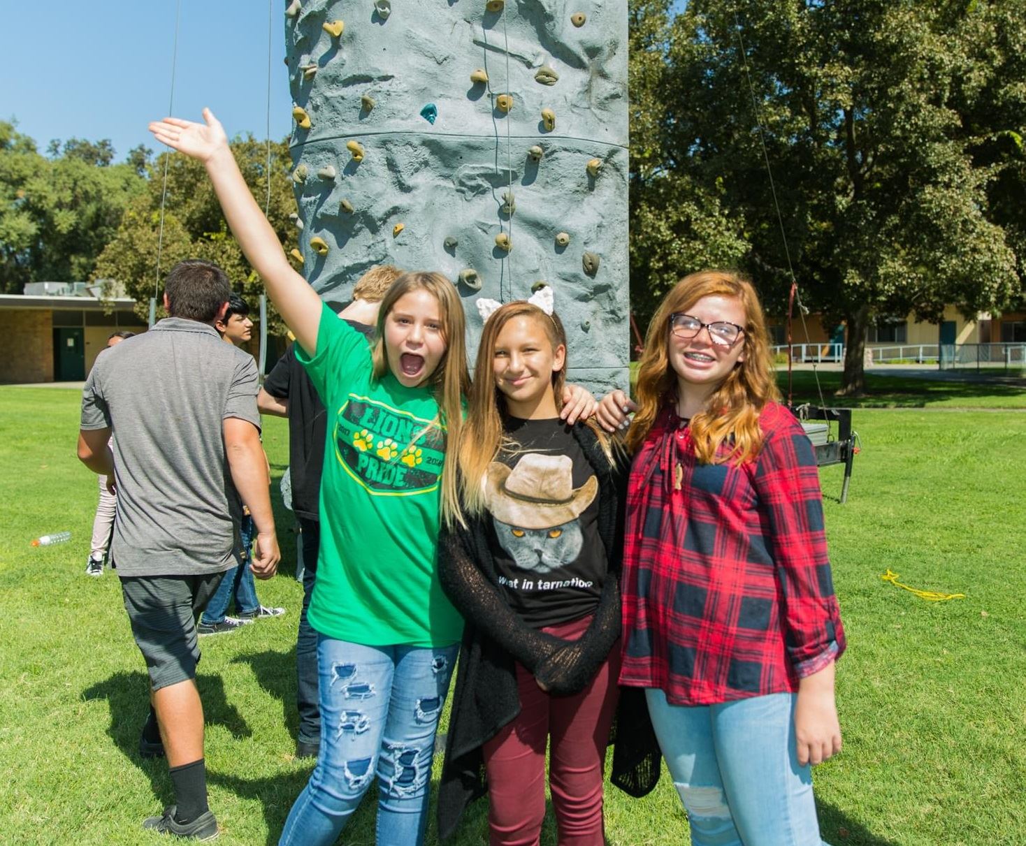 Three girls by rock climbing wall